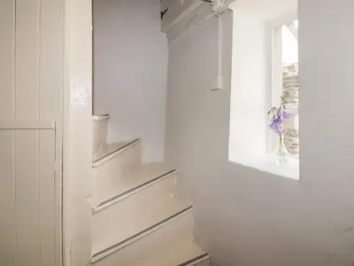 a room with stairs and a window and a vase of flowers at Kooky Cottage in Brecon