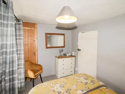 a bedroom with a bed and a dresser and a mirror at Kooky Cottage in Brecon
