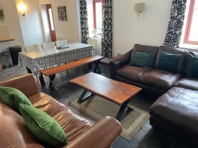 a living room with leather furniture and a table at The Stable in Aberystwyth