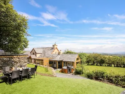 an external view of a house with a table and chairs at Hafotty Gelynen in Corwen