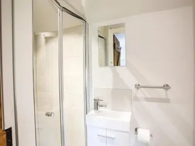 a white bathroom with a sink and a shower at Hafotty Gelynen in Corwen