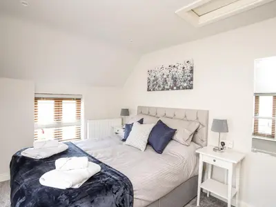 a white bedroom with a large bed with blue pillows at Hafotty Gelynen in Corwen