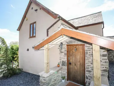a stone cottage with a wooden door at Hafotty Gelynen in Corwen