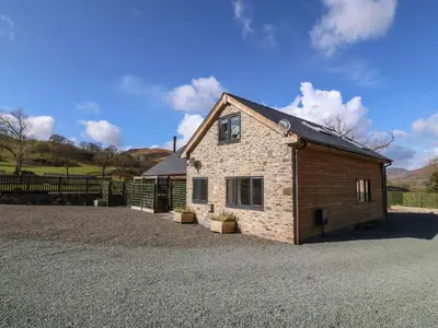 a small brick house sitting on top of a gravel driveway at Y Stabl The Stable in Oswestry