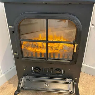a black stove with a fire inside of it at Hilltop Hut in Church Stretton