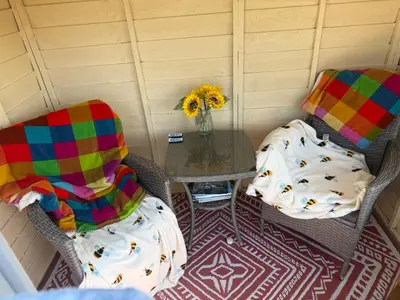 a room with two chairs and a table with a vase of flowers at Hilltop Hut in Church Stretton