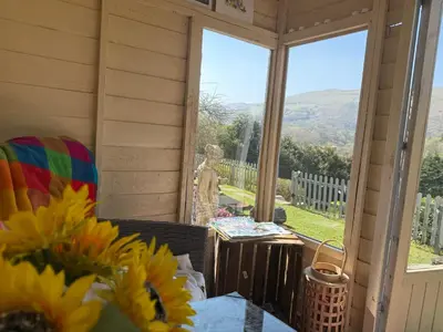 a screened in porch with a view of the mountains at Hilltop Hut in Church Stretton