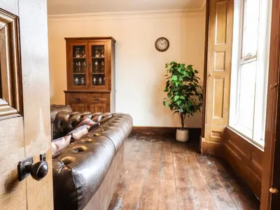 a leather couch in a living room with a clock on the wall at Bodaioch Hall in Caersws