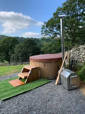 a sauna with a bench and a table and a stove at Safari Tent with Hot Tub in heart of Snowdonia in Dolgellau
