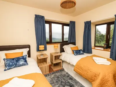 two beds in a bedroom with blue curtains at Pant Y Rhedyn in Llandrindod Wells
