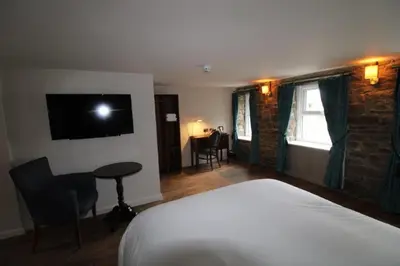 a bedroom with a bed and a desk and a television at rooms @ the dolau inn in New Quay