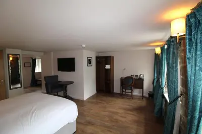 a hotel room with a bed and a table and chairs at rooms @ the dolau inn in New Quay