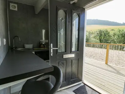 a kitchen with a counter and a door with a balcony at Caban Glas in Aberystwyth