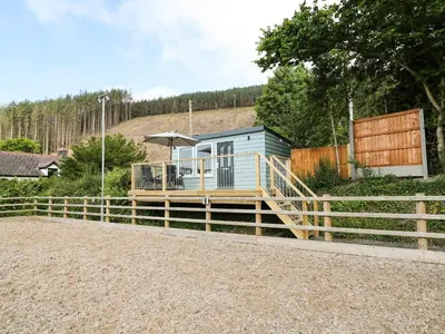 a tiny house with a deck and a fence at Caban Glas in Aberystwyth