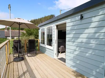a deck with an umbrella and a building at Caban Glas in Aberystwyth