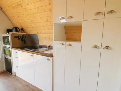 a kitchen with white cabinets and a sink at Seren in Llandrindod Wells