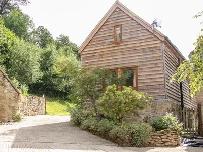 a small wooden house with a tree in front of it at Pool Barn in Craven Arms