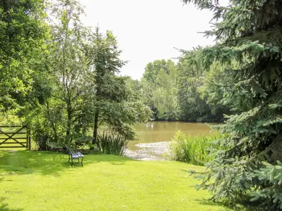 a bench sitting in the grass next to a river at Pool Barn in Craven Arms