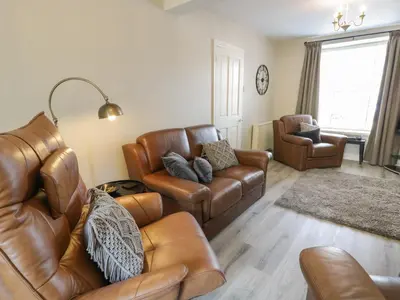 a living room with a leather couch and chairs at Minffordd in Blaenau-Ffestiniog