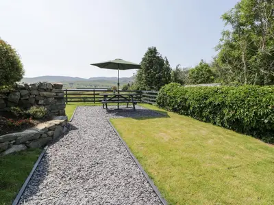 a picnic table with an umbrella in a garden at Minffordd in Blaenau-Ffestiniog