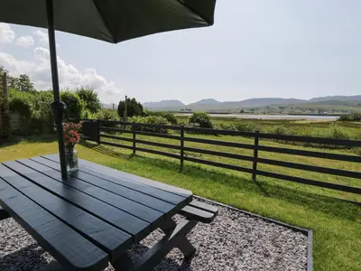 a picnic table with an umbrella in front of a fence at Minffordd in Blaenau-Ffestiniog