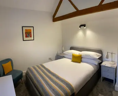 a bedroom with a large bed and a blue chair at The Retreat in Bredwardine