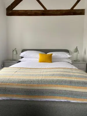 a bedroom with a large bed with a yellow pillow at The Retreat in Bredwardine