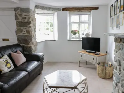 a living room with a leather couch and a tv at The Toll House in Dolgellau