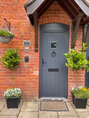 a gray door on a brick house with two potted plants at Hayes Suite in Oswestry