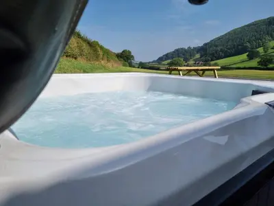 a bath tub filled with water next to a picnic table at Meadow View in Meifod