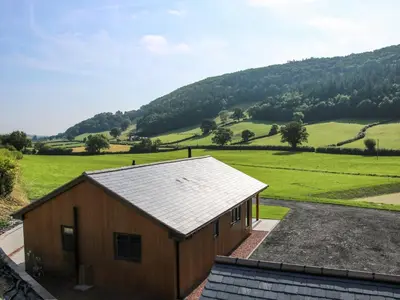 a small building with a mountain in the background at Meadow View in Meifod