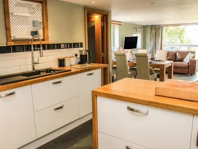 a kitchen with white cabinets and a living room at Sunnyside in Leominster
