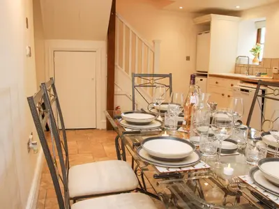 a dining room with a table with plates and glasses at Linley Lane Cottage in Bishops Castle