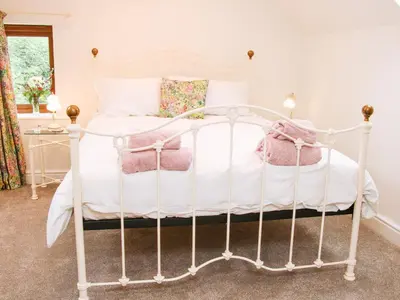 a white bed with pink pillows on it at Linley Lane Cottage in Bishops Castle