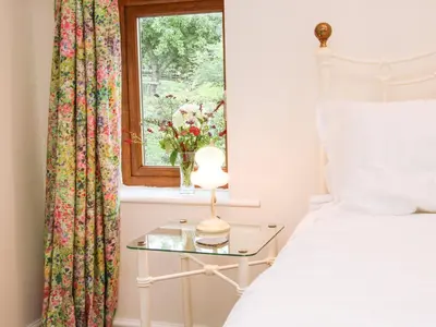 a bedroom with a bed and a glass table with a window at Linley Lane Cottage in Bishops Castle