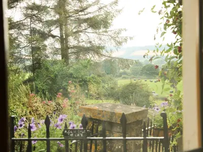 a view of a garden with a table and flowers at Linley Lane Cottage in Bishops Castle