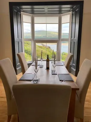 a dining table with a bottle of wine and chairs at No6 in Barmouth