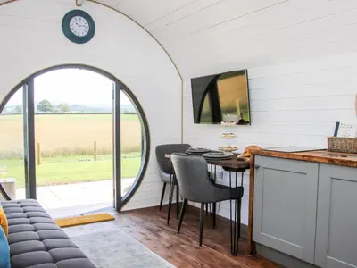 a kitchen with a table and chairs and a clock at Withy Willows in Craven Arms
