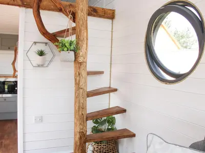 a wooden spiral staircase in a tiny house with a mirror at Cherry Blossom in Craven Arms