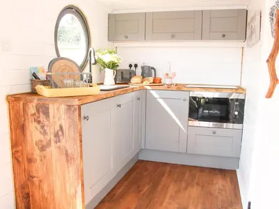 a kitchen with white cabinets and a wooden floor at Cherry Blossom in Craven Arms