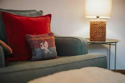 a couch with a red pillow and a table with a lamp at 13 Tabernacle Street - Aberaeron in Aberaeron