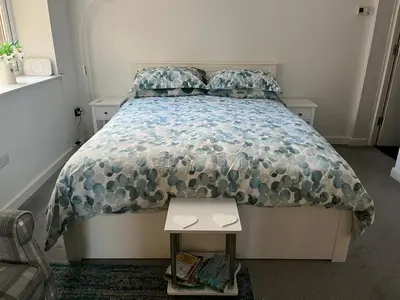 a bedroom with a bed with a comforter and a table at Flat 2 Frank Lewis House in Hay-on-Wye