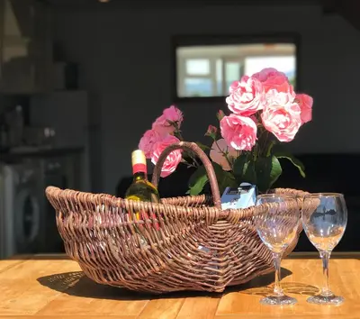 a basket of flowers and wine glasses on a table at 2 Bed Rural cottage between the mountains and Sea in West Wales in Lampeter