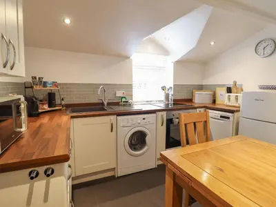 a kitchen with a washer and a sink and a dishwasher at Arthurs Cottage in Tywyn