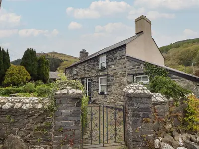 an old stone house with a gate at Arthurs Cottage in Tywyn