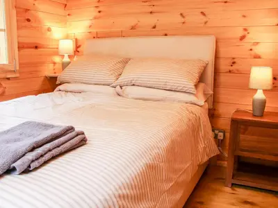 a bedroom with a large bed with wooden walls at Callow Fold in Craven Arms