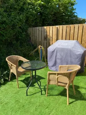 two chairs and a table in a yard with a fence at The Pod in Aberystwyth