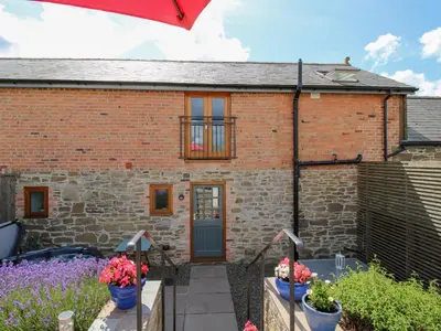 a brick house with a garden in front of it at Meadow Barn in Craven Arms