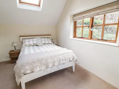 a white bedroom with a bed and a window at Tan Y Garth Cottage in Corwen