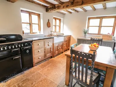 a kitchen with a wooden table and a black stove at Tan Y Garth Cottage in Corwen